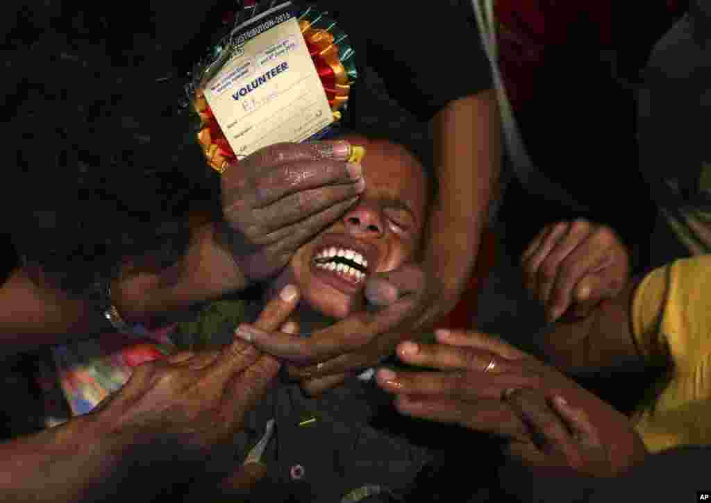 Volunteers try to open the mouth of a child suffering from asthma to administer "fish medicine", in Hyderabad, India.