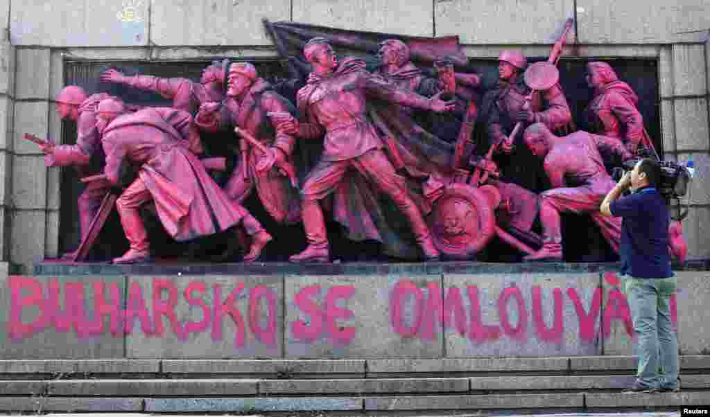 A cameraman films the figures of Soviet soldiers at the base of the Soviet Army monument painted in pink in Sofia. Unknown artists have painted the nine soldiers in pink during the night and wrote "Bulgaria apologizes" both in Bulgarian and Czech language in what appears to be an artistic apology for Bulgaria's support in smashing the Prague Spring uprising against the Communist rule in August, 1968.