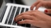 A person types on a laptop computer in Manhattan, New York City