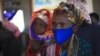 FILE - A woman waits for the AstraZeneca coronavirus vaccine at the Butanda Health Center III in Western Uganda, April 27, 2021.