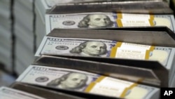 FILE - Freshly cut stacks of $100 bills make their way down the line at the Bureau of Engraving and Printing Western Currency Facility in Fort Worth, Texas.