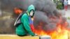 FILE - A demonstrator sits next to a fire barricade on a street during a rally against Venezuela's President Nicolas Maduro in Caracas, Venezuela, April 24, 2017.