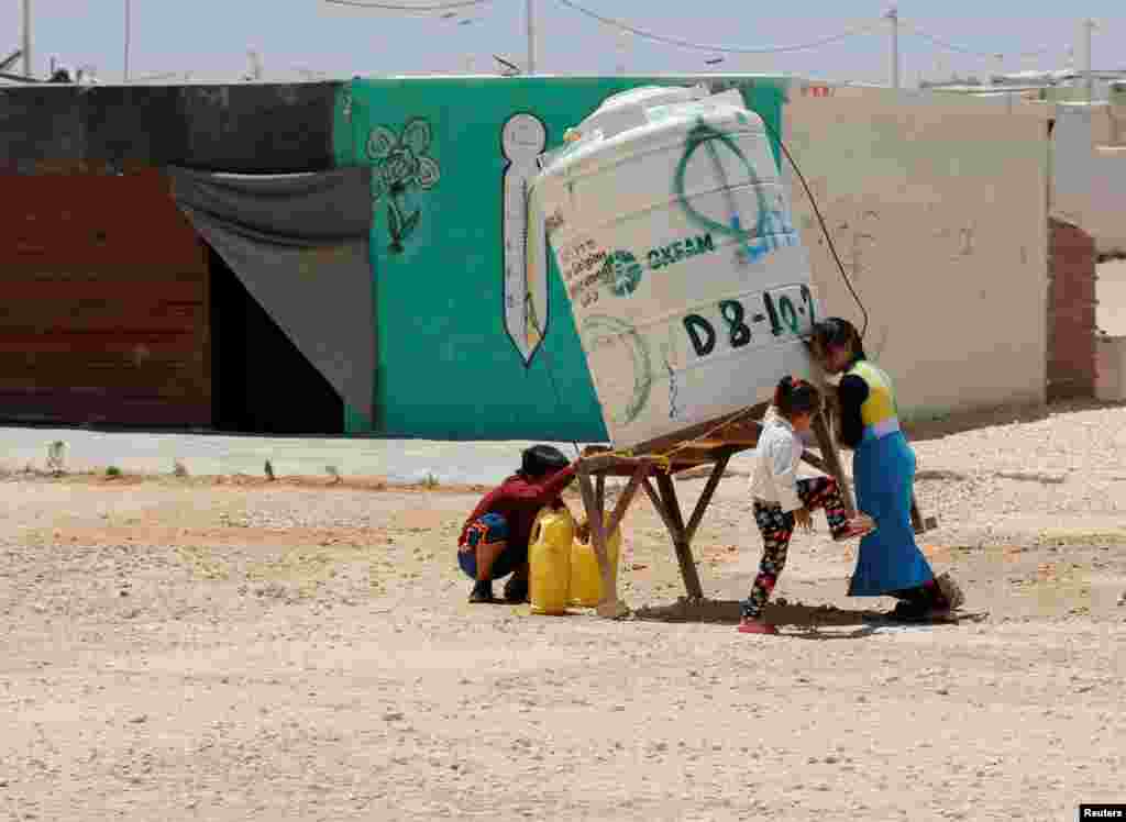 Syrian refugee children collect water at the Al-Zaatari refugee camp in Mafraq, Jordan, near the border with Syria.