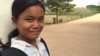 កុមារី​គុល ស្រីម៉ៅ ឈរ​នៅ​មុខ​សាលារៀន​របស់​នាង​ដែល​លោកស្រី Michelle Obama ភរិយា​ប្រធានាធិបតី​សហរដ្ឋ​អាមេរិក បាន​ទៅ​ធ្វើ​ទស្សនកិច្ច​នៅ​ខែមីនា​ឆ្នាំ២០១៥ ដើម្បី​ផ្សព្វផ្សាយ «គម្រោង​ផ្តល់​ឱកាស​ឲ្យ​ក្មេង​ស្រី​បាន​សិក្សា» «Let Girls Learn»។