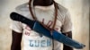 In this April 15, 2014 photo, an Anti-Balaka Christian fighter stands on the front of a looted Muslim store in Guen, some 250 kilometers north of Bangui, Central African Republic. As U.N. peacekeepers prepare to go into the Central African Republic to take over a regional mission, the death toll since fighting between Muslims and Christians started in December underscores how the aid is coming too late for thousands of victims. (AP Photo/Jerome Delay)