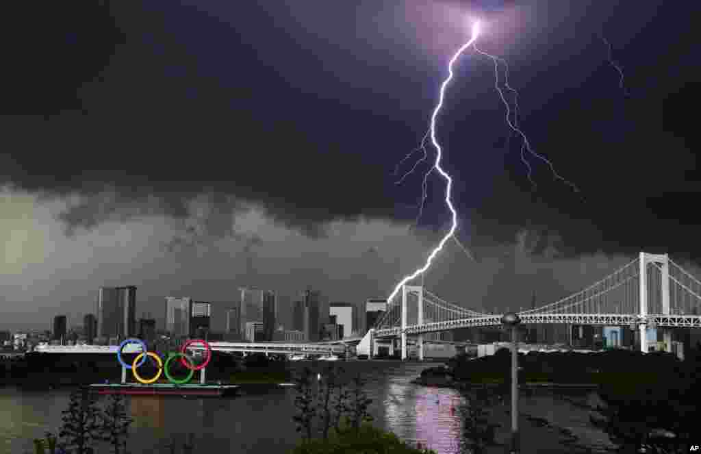 Lightning illuminates the sky over the Olympic rings and the Rainbow Bridge in Tokyo, Japan.