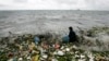 File - A man collects recyclable plastic materials, washed ashore by waves in Manila.