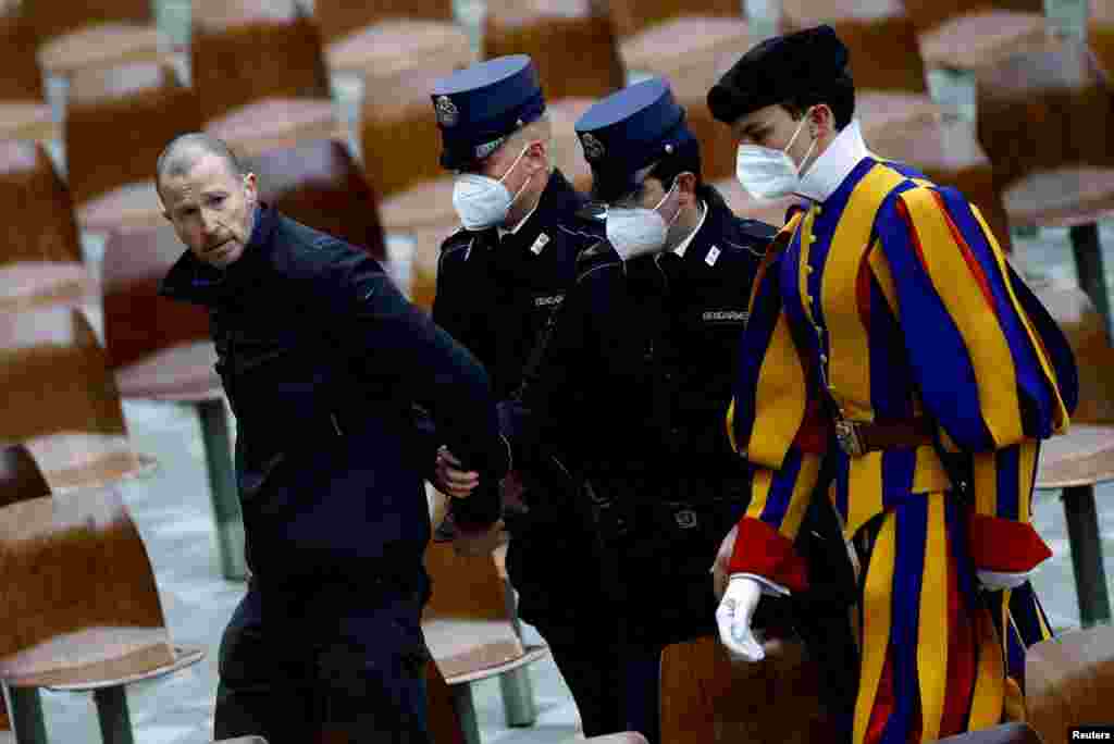 Members of the gendarmerie and a member of the Pontifical Swiss Guard escort out of the Vatican a man who interrupted Pope Francis&#39; weekly general audience.