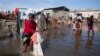 Bernard Sylphanie cleans her belongings in floodwater outside her home in Cap-Haitien, Haiti, Friday, Nov. 7, 2014. Thousands of families in Haiti and the neighboring Dominican Republic have been affected by floods from a storm system that drenched the countries for several days. At least five people were killed and one was missing. Floods raise the risk of cholera and dysentery outbreaks. (AP Photo/Dieu Nalio Chery)