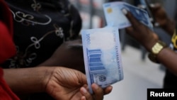 Mtu akiwa ameshika noti mpya ya Naira 1000 huku Benki Kuu ya Nigeria ikitoa noti hizo kwa umma kupitia benki za Abuja.Desemba 15, 2022. REUTERS 