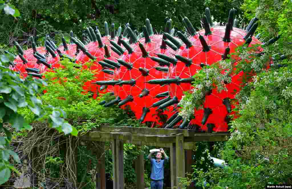 A man takes a picture of the art installation 'Visitors' by artist Andre Tempel from Dresden at the Frommannsche Skulpturen garden in Jena, Germany.