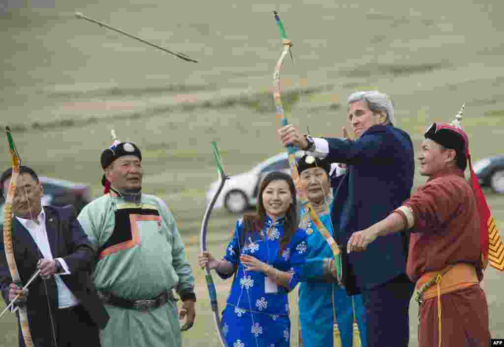 U.S. Secretary of State John Kerry shoots a bow and arrow as he participates in a Naadam ceremony, a competition which traditionally includes horse racing, Mongolian wrestling and archery, in Ulan Bator, Mongolia.
