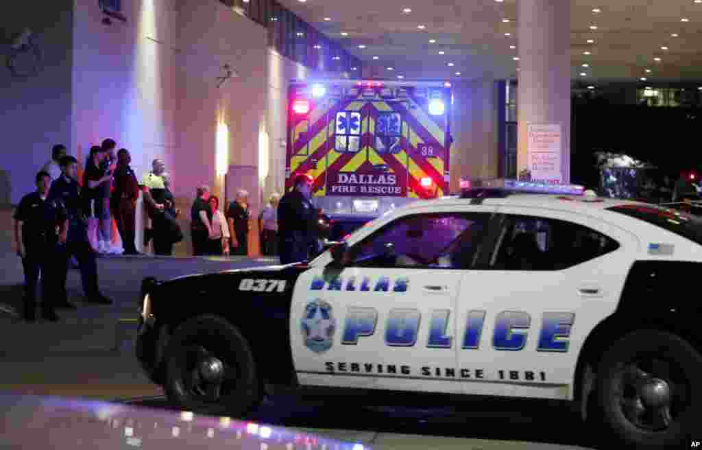 Des policiers et d’autres personnes émotionnés s’appuient contre un mur à l’arrivée d’une ambulance transportant un blessé au service d'urgence au centre médical de l'Université de Baylor, à Dallas, 8 juillet 2016. (AP Photo / Tony Gutierrez)