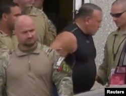 FILE - Cesar Sayoc, who was arrested during an investigation into a series of parcel bombs, is escorted from an FBI facility in Miramar, Florida, Oct. 26, 2018 in a still image from video.