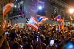 FILE - People celebrate outside the governor's mansion La Fortaleza, after Gov. Ricardo Rossello announced that he is resigning Aug. 2 after nearly two weeks of protests and political upheaval, in San Juan, Puerto Rico, July 25, 2019.