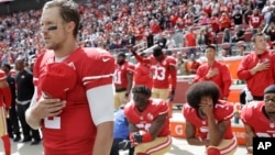 FILE - San Francisco 49ers quarterback Blaine Gabbert, left, stands as Eli Harold, from bottom left, Colin Kaepernick and Eric Reid kneel during the national anthem before an NFL football game in Santa Clara, California, Oct. 2, 2016.