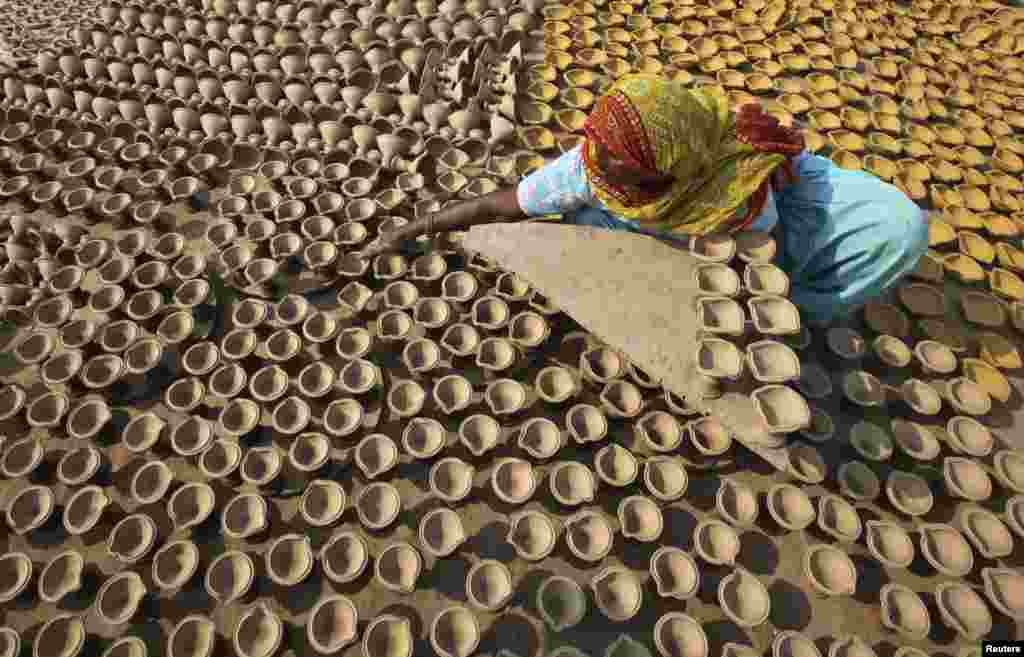 A woman puts out earthen lamps to dry in the sun at her workshop ahead of the Hindu festival of Diwali in the northern Indian city of Chandigarh.