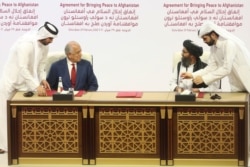FILE - In this Feb. 29, 2020 photo, U.S. peace envoy Zalmay Khalilzad, left, and Mullah Abdul Ghani Baradar, the Taliban group's top political leader sign a peace agreement in Doha, Qatar.