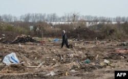 FILE - A man walks among remains of taken down shelters during the dismantling of the southern part of the so-called "Jungle" migrant camp in Calais, northern France, March 10, 2016.