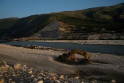 FILE - An abandoned bulldozer sits on the banks of the Vjosa River at the construction site of the Kalivac dam in Albania, June 23, 2019.