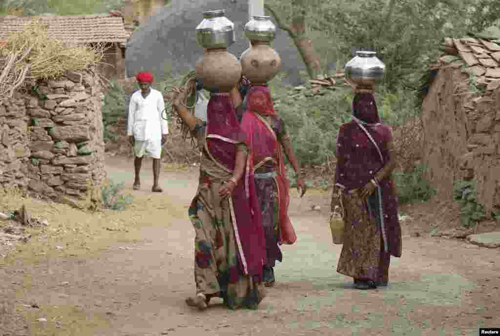Women carry pitchers filled with drinking water in Devmali village in the desert state of Rajasthan, India.