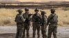 FILE - U.S. soldiers stand at an oil field in the countryside of al-Qahtaniyah town in Syria's northeastern Hasakeh province near the Turkish border, Aug. 4, 2020.