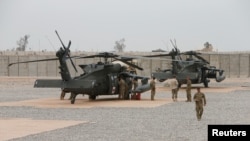 FILE - U.S. Army soldiers stand next to helicopters at Qayyarah West Airfield, Iraq, March 1, 2017. Seven U.S. service members were killed Thursday when their helicopter went down near the town of Al Qaim in Iraq's Anbar province. 