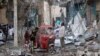 People stand on the rubble of buildings damaged when a suicide car bomb exploded, targeting a Mogadishu hotel in a business center in Maka al-Mukaram street, Mogadishu, Somalia, March 1, 2019. 