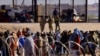 FILE - Migrants stand near the United States/Mexico border wall, as seen from Ciudad Juarez, Mexico. U.S. immigration officials reported more than 2 million migrant encounters along U.S. borders nationwide in fiscal 2022. 