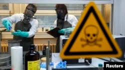 Employees of an OPCW-linked lab inspect dummy samples contaminated with a substance similar to Sarin during demonstration, Munster, Oct. 15, 2013.
