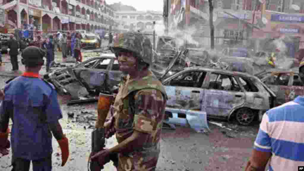 Un soldat nigérian, centre, marche sur les lieux d'une explosion à Abuja, au Nigeria. Boko Haram a été accusé pour cet attentat qui a couté la vie à des dizaines de personnes à Maiduguri, lieu où le groupe islamiste extrémiste est né. (AP Photo / Olamikan Gbemiga, File)