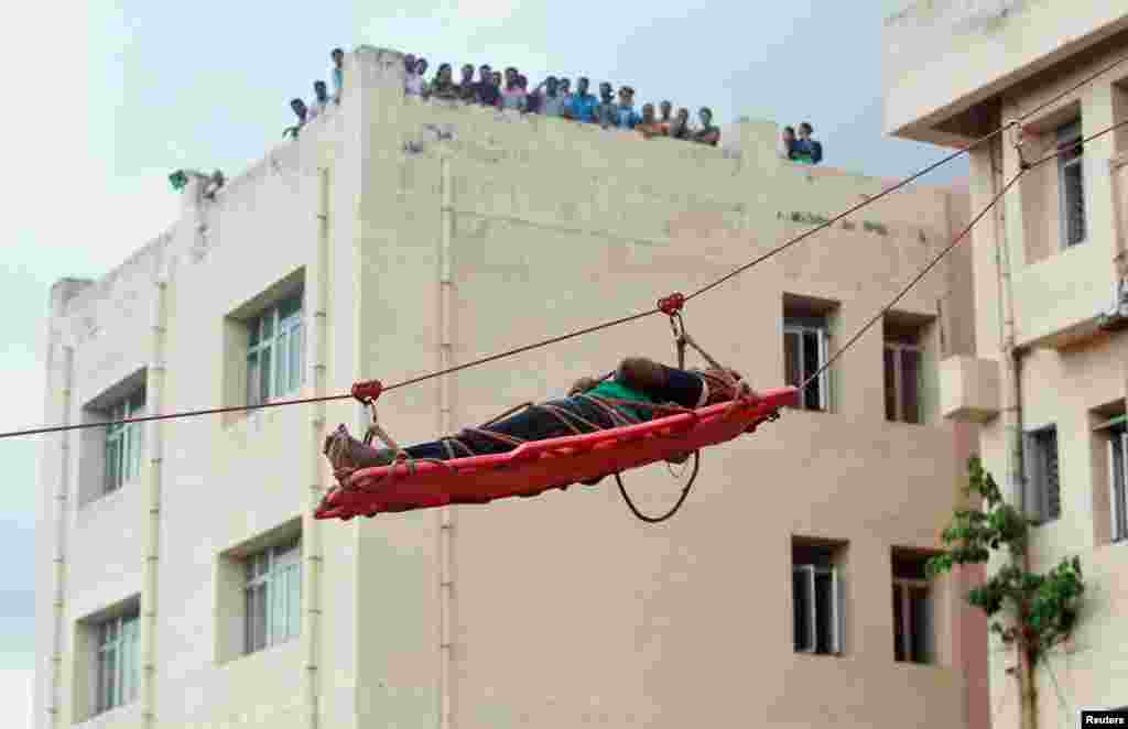 A simulated victim is lowered on a stretcher during an earthquake drill in Agartala, India.