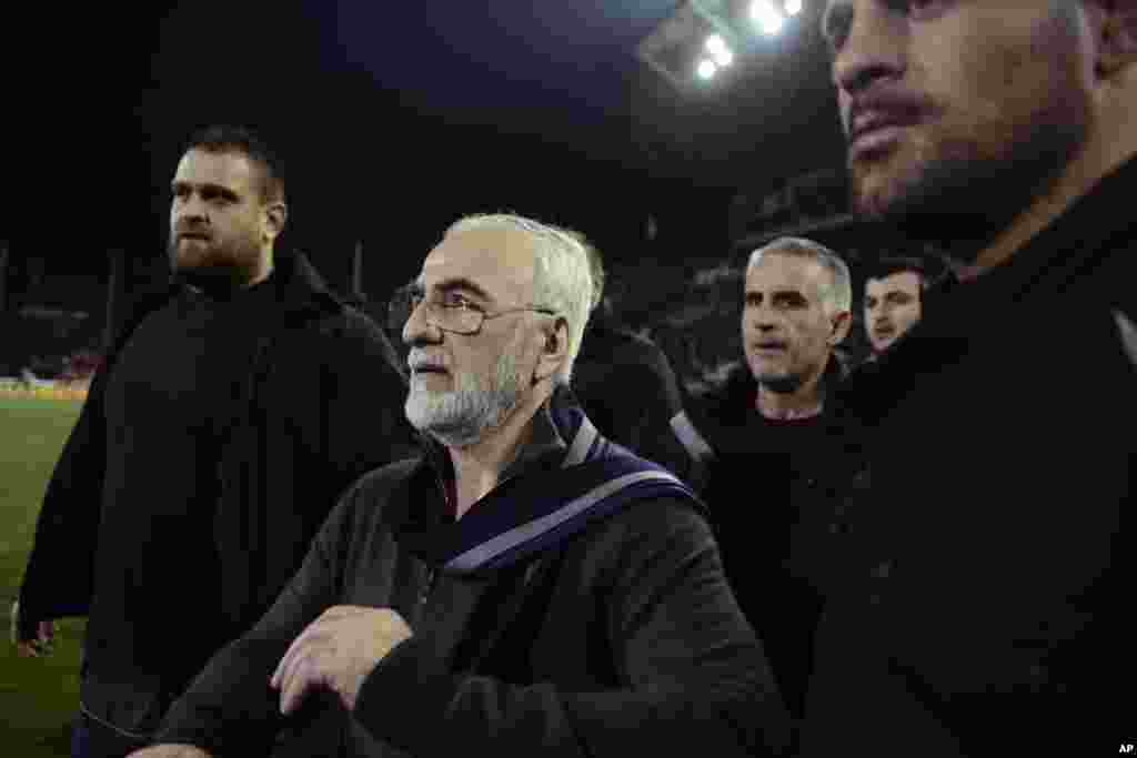 Mai kungiyar PAOK, Ivan Savvidis, rataye da bindiga a kunkuminsa, tare da masu gadinsa, a lokacin da ya kutsa cikin filin wasa a karawarsu da AEK Athens ranar lahadai a birnin Thessaloniki. Sau biyu Savvidis yana kutsawa cikin filin a lokacin wasa. Jami'an AEK sun yi zargin cewa Savvidis yayi barazana ga alkalin wasan a kutsawarsa ta farko, kafin masu gadinsa su janye shi. A karo na biyu an ga bindiga a rataye a kunkuminsa.(InTime Sports via AP)