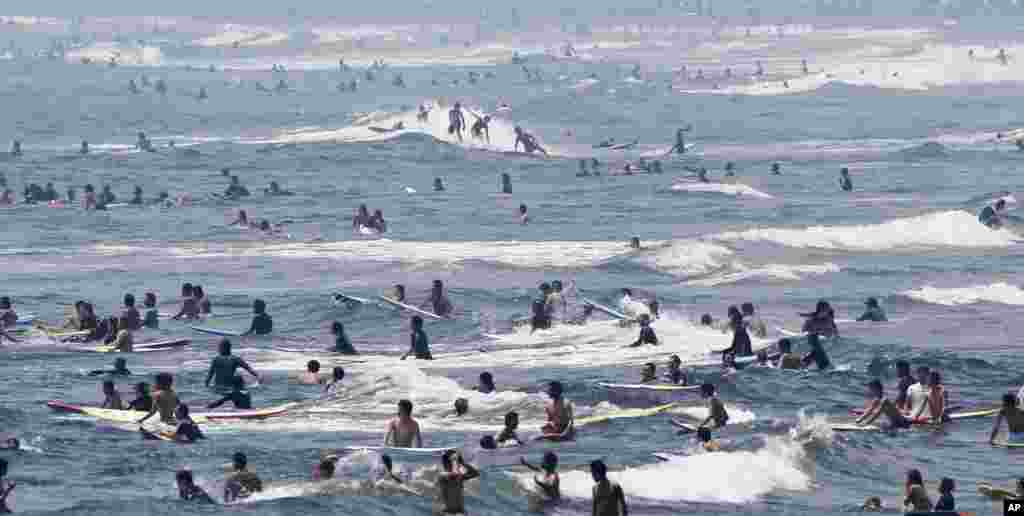 Para peselancar bermain di pantai Shonan, kota Fujisawa, sebelah barat Tokyo, Jepang, sementaar gelombang udara panas melanda Jepang.