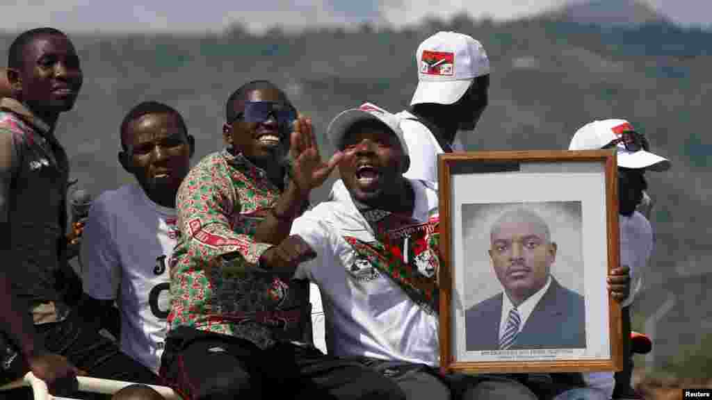 Des partisans du président du Burundi, Pierre Nkurunziza, jonchés sur un véhicule avec son effugie en mains, attendent le passage de son convoi dans la capitale, dans une rue à Bujumbura, après un coup d'Etat manqué au Burundi, le 15 mai 2015.