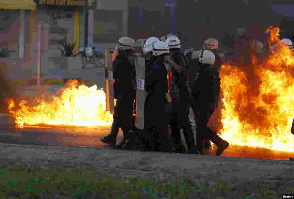 Riot police advance behind the cover of their shields as flames from Molotov cocktails thrown by anti-government protesters burn around them during clashes in Budaiya, west of Manama, Bahrain.