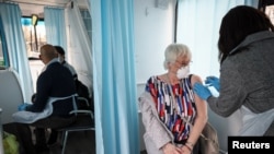 A woman receives a dose of the Oxford-AstraZeneca COVID-19 vaccine inside a mobile vaccination center for the COVID-19, in Thamesmead, London, Feb. 14, 2021. 
