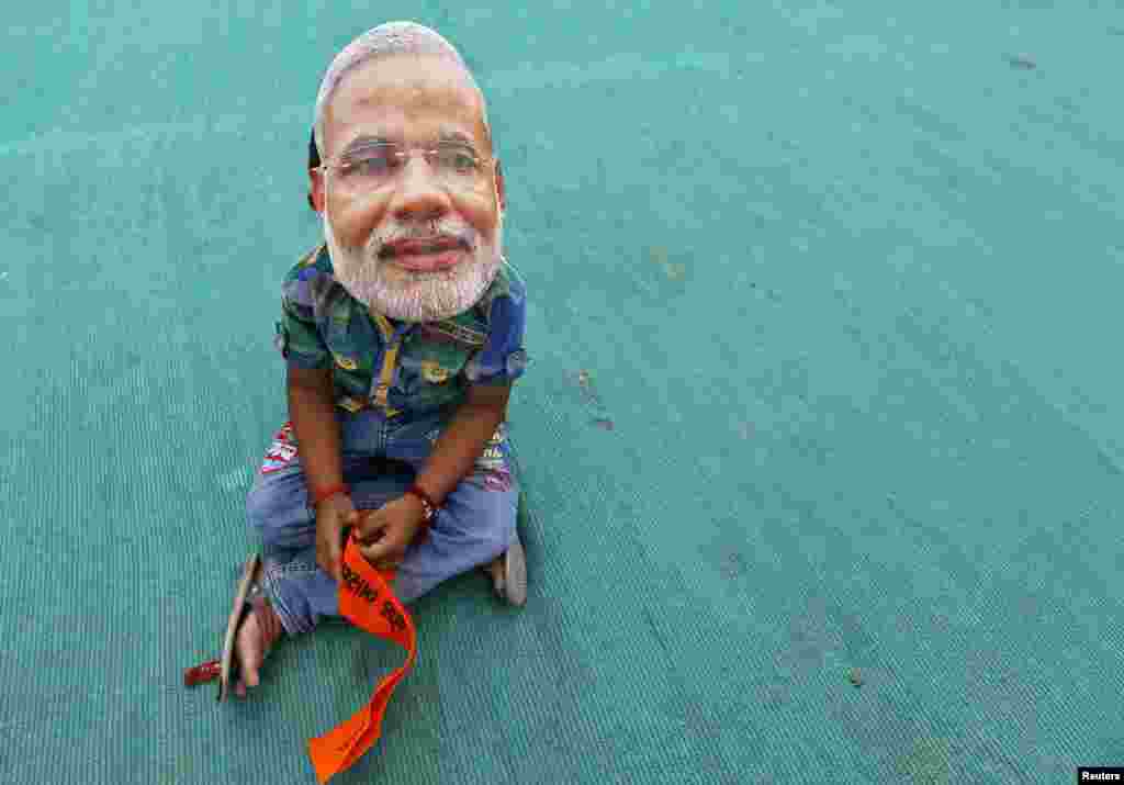 Seorang anak mengenakan topeng tokoh oposisi India, Narendra Modi dari partai Bharatiya Janata (BJP), menunggu kampanye yang menghadirkan Modi sebagai pembicara di Kheralu, negara bagian Gujarat.