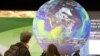FILE - People watch the Earth globe at the COP21, the United Nations conference on climate change in Le Bourget, Dec. 10, 2015. 