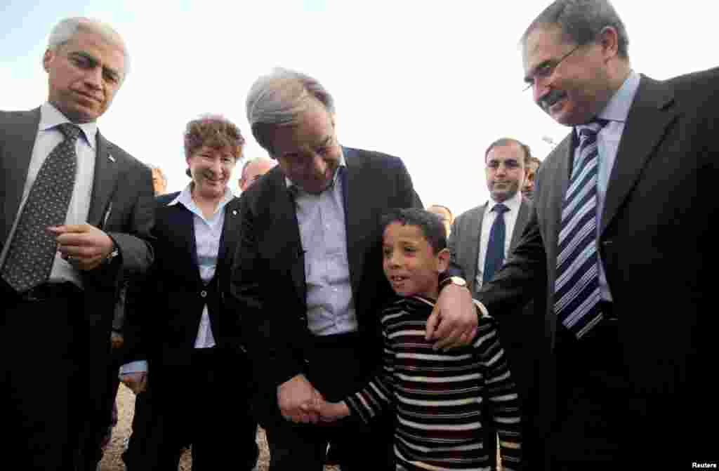 United Nations High Commissioner for Refugees (UNHCR) Antonio Guterres (C) walks with a Syrian refugee boy at a camp in Nizip, Turkey, March 10, 2013.