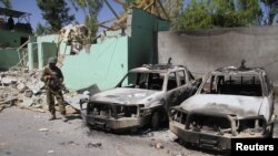 Seorang anggota pasukan keamanan Afghanistan mengawasi dua kendaraan yang rusak setelah serangan Taliban di Ghazni City, Afghanistan, 15 Agustus 2018. (Foto: Reuters/Ilustrasi)