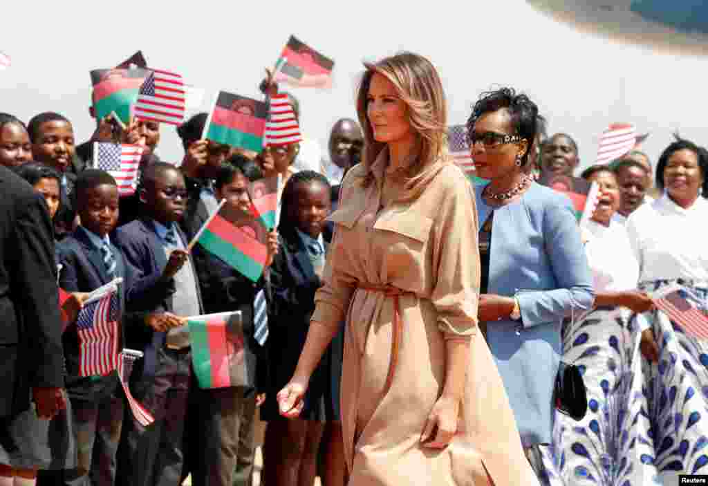 U.S. first lady Melania Trump walks past children holding flags as she arrives in Lilongwe, Malawi, Oct. 4, 2018.