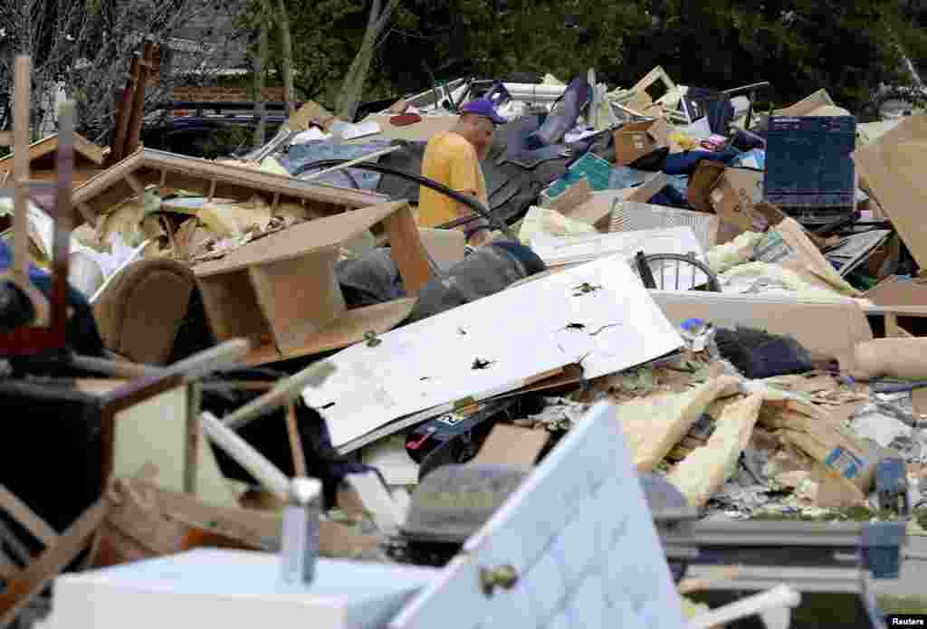 A man walks through piles of debris in front of flood-damaged homes at the South Point subdivision in Denham Springs, Louisiana, Aug. 22, 2016.