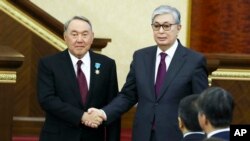Presiden sementara Kazakhstan Kassym-Jomart Tokayev (kanan) dan Presiden Kazakhstan yang mengundurkan diri, Nursultan Nazarbayev, berjabat tangan setelah upacara pelantikan di Astana, Kazakhstan, Rabu, 20 Maret 2019.