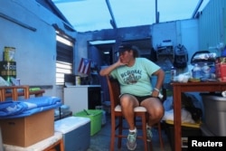 Jazmin Morales sits in her kitchen without power and with a plastic sheet replacing the roof in Yabucoa, Jan. 29, 2018.