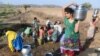 Indian Lambadi tribal villagers fill drinking water from a leaking pipe on a roadside at Chandampet Mandal in Nalgonda east of Hyderabad on April 25, 2016, in the southern Indian state of Telangana.