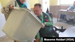یو معذور رایه ورکوونکی چې پخپلې خولې صندوق ته خپله رایه اچوي