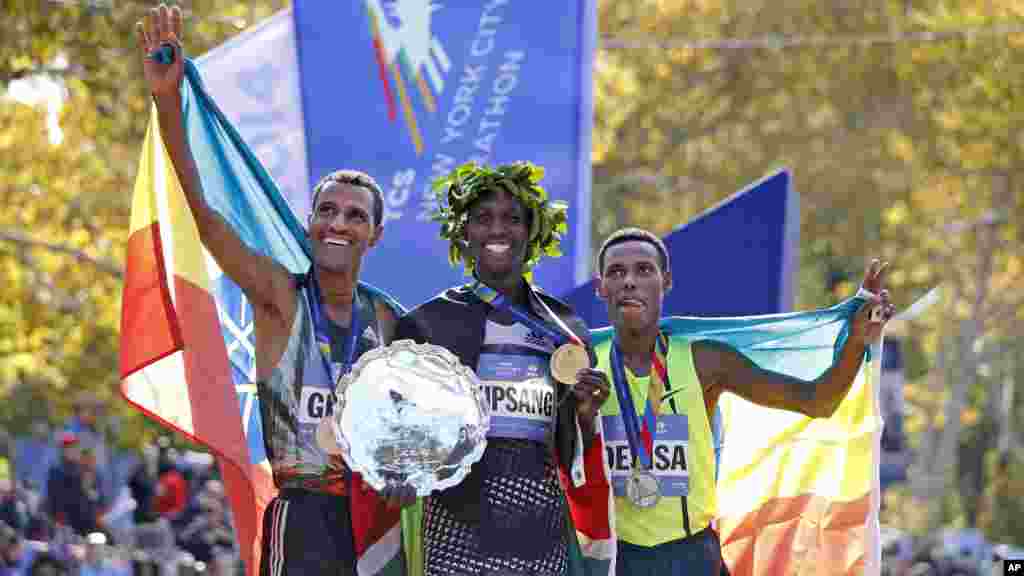 Le vainqueur chez les hommes, Wilson Kipsang, centre, est rejoint par le deuxième au classement, Lelisa Desisa Benti, des États-Unis, à gauche, et le troisième, Gebre Gebremariam, de l'Ethiopie, au terme du 44ème annuel Marathon de New York à New York, le 2 novembre 2014.