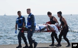 In this photo released by Japan's Defense Ministry, an injured USS Fitzgerald crew member is carried by U.S. military personnel, left, and Japanese Maritime Self-Defense Force members upon arriving at the U.S. naval base in Yokosuka, southwest of Tokyo, June 17, 2017.
