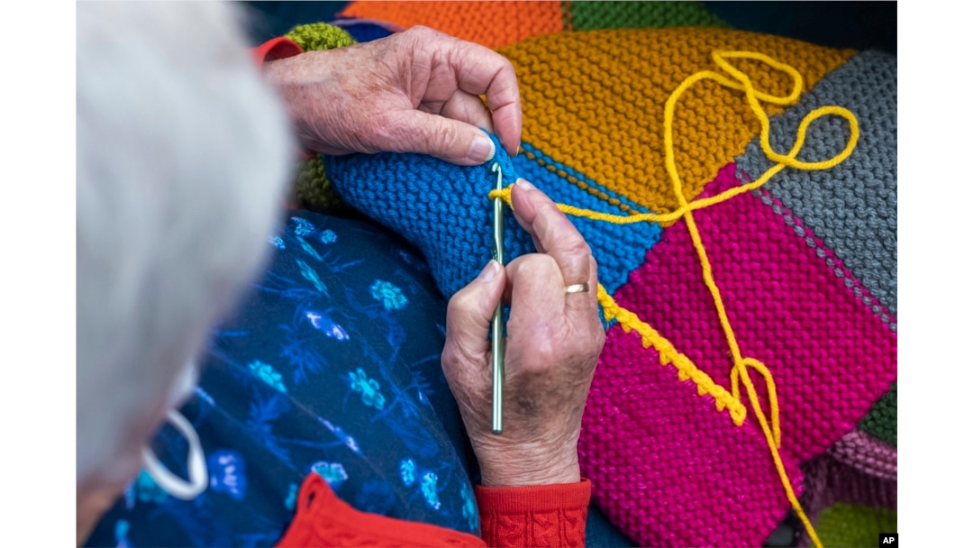 In this photo provided by Edward Boches, a volunteer adds a border to a blanket, Jan. 8, 2023 in Brookline, Mass. The Welcome Blankets will be donated to agencies helping immigrants who recently arrived in the United States. (Edward Boches via AP)